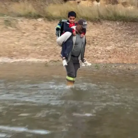 Oğlunu okula gönderebilmek için her gün sırtına alıp ırmaktan geçiriyor