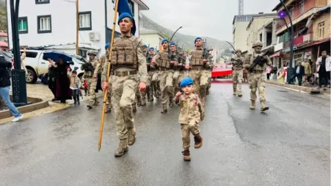 Şırnak'ta küçük çocuk yağmurlu havaya rağmen 29 Ekim kutlamalarında askerlerin kortejine eşlik etti