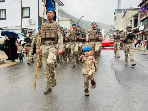 Şırnak'ta küçük çocuk yağmurlu havaya rağmen 29 Ekim kutlamalarında askerlerin kortejine eşlik etti