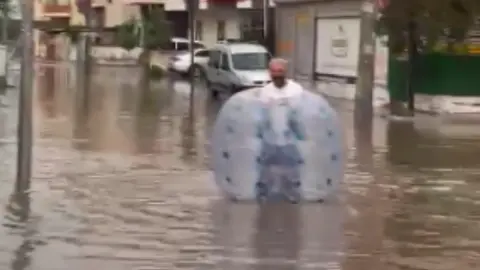 Mersin'de göle dönen caddede şişme balonla yüzdü: Muhtar öğrenciyi omzunda taşıdı